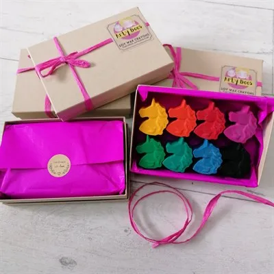 Open box of unicorn crayons with gift wrapped boxes surrounding.
