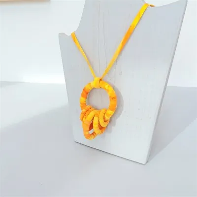 Yellow fabric pendant necklace hanging on a display stand