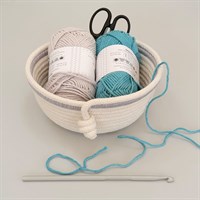 Cotton rope bowl with light grey trim filled with balls of wool and crochet hook