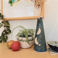 Tall conical blue ceramic vase in room setting